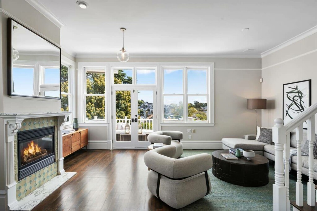 Living room at 1793 Sanchez St, with fireplace, chairs, couch, and French doors to balcony backing to a tree.