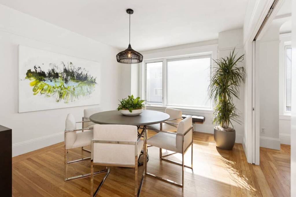 Dining room with updated lighting, round table, window, painting and five chairs, in a Glen Park home we helped to sell.