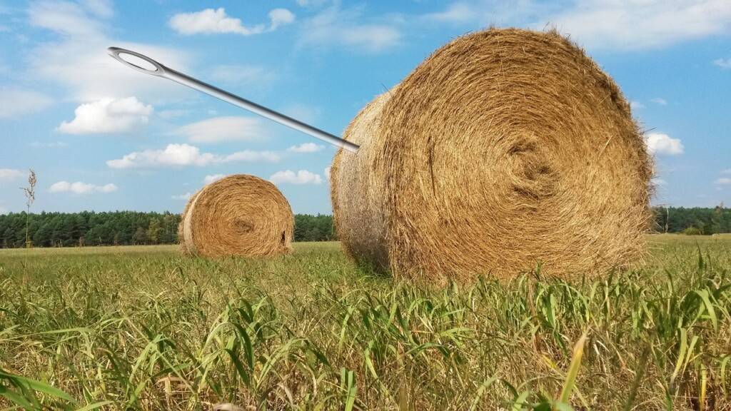 Giant needle sticking out of a cylindrical hay bale.