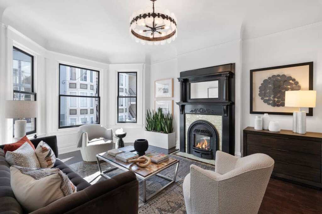 Elegant living room interior featuring an Edwardian fireplace, hardwood floors, and large windows for natural light